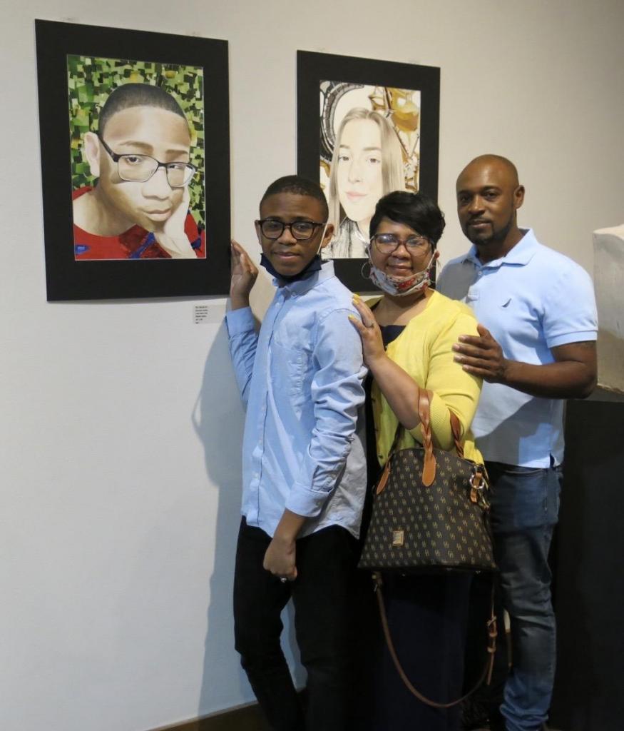 Michael Landry, with his parents Lakeha and Charles Payton, shows his mixed media self-portrait &quot;Me, Myself, and I&quot;.